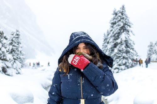 蓝色拉链连帽外套站在雪地上的女人 · 免费素材图片