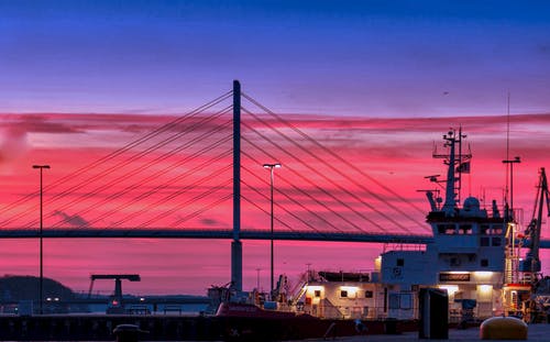 在红云和蓝天在夜间拍摄下的一座桥的轮廓 · 免费素材图片
