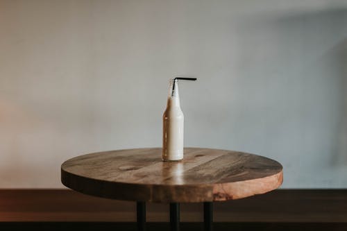 玻璃瓶装满棕色木制的桌子上的黑色稻草 · 免费素材图片