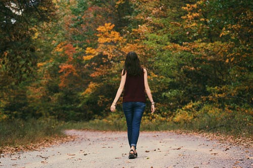 棕色无袖连衣裙和蓝色的牛仔裤，站在灰色的道路上的女人 · 免费素材图片