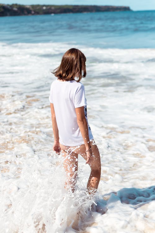 白色上衣，走在海滩边的女人 · 免费素材图片