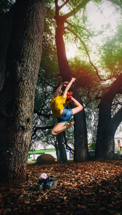 黄色的衬衫和蓝色的牛仔短裤，在树林里做芭蕾舞的人 · 免费素材图片