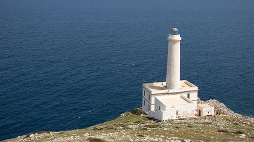 水体附近悬崖上的白色灯塔 · 免费素材图片