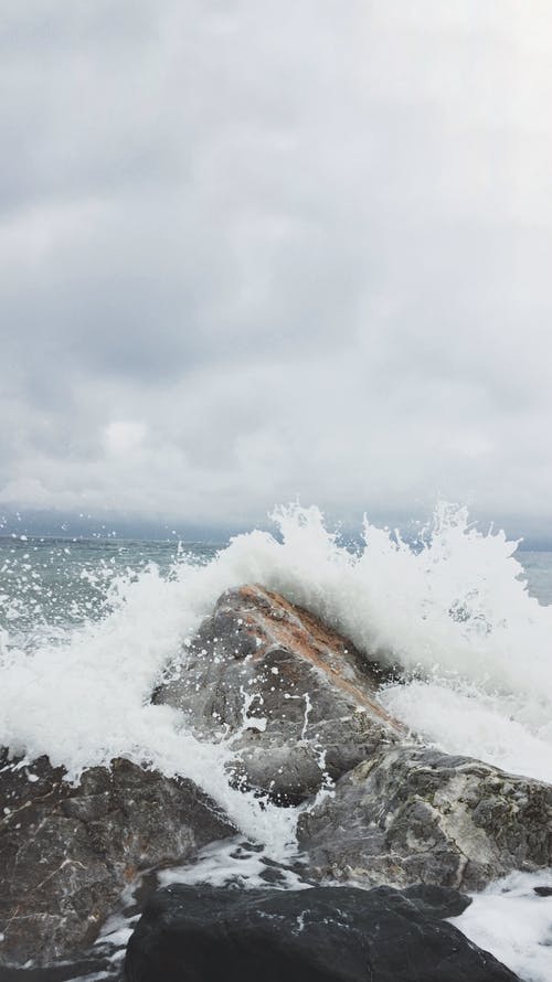 拍张海浪和灰色混凝土岩石的人 · 免费素材图片