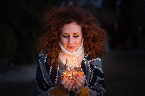 女人抱着装满灯的透明玻璃罐 · 免费素材图片