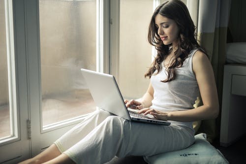 女人穿着背心坐在窗边 · 免费素材图片