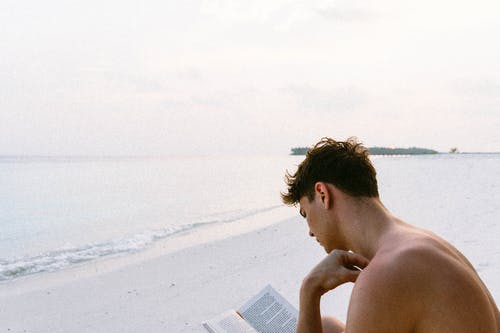 坐在海滩上的裸照人看书 · 免费素材图片