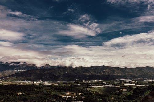 白多云的天空下山附近草地的航拍 · 免费素材图片