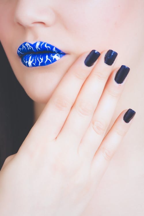 女人穿着黑色修指甲的蓝色和白色唇膏 · 免费素材图片