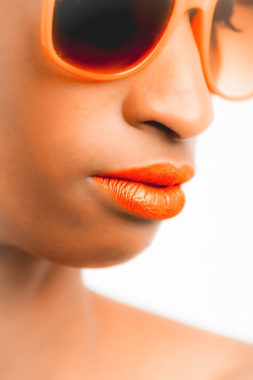 女人戴着橙色镜框太阳镜和橙色唇膏 · 免费素材图片
