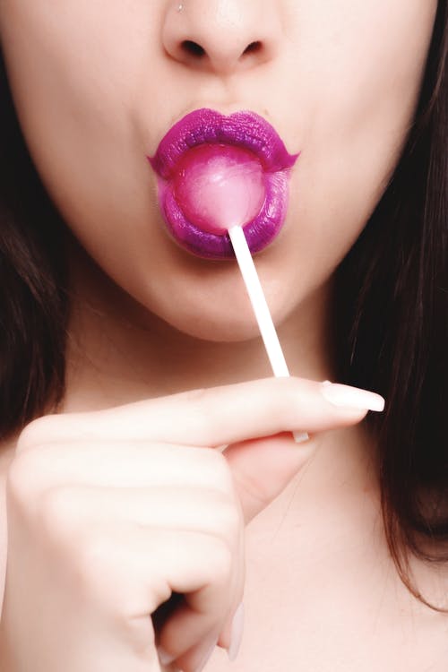 粉色口红舔草莓棒棒糖的女人 · 免费素材图片