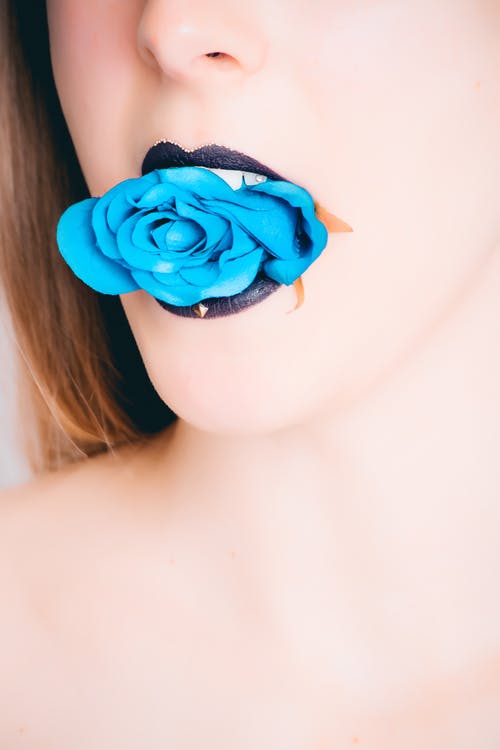 黑色唇膏咬蓝玫瑰的女人 · 免费素材图片