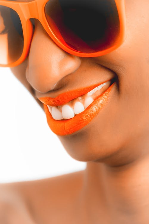 女人穿着橙色镜框太阳镜和橙色唇膏 · 免费素材图片