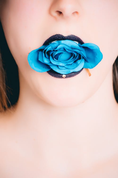 女人在嘴上戴黑色玫瑰与蓝玫瑰 · 免费素材图片