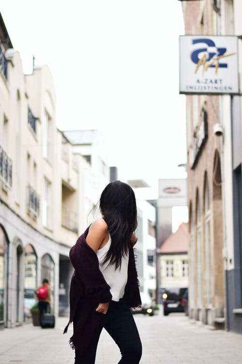 女人穿着白色背心与褐红色夹克穿越n街 · 免费素材图片