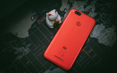 白猫公仔旁边的红色小米mi智能手机 · 免费素材图片