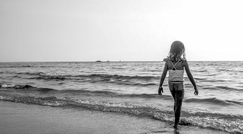 女孩走在海边与白色意大利面条皮带顶部的灰度照片 · 免费素材图片