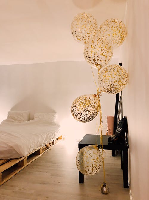 白色床罩套附近的气球 · 免费素材图片