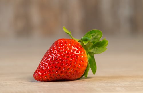 草莓果实棕色木制表面上 · 免费素材图片