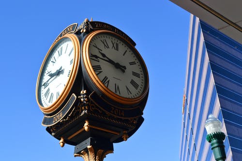 高层建筑附近的街道时钟的特写照片 · 免费素材图片