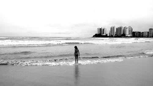 女性站立的海滨的灰度照片 · 免费素材图片