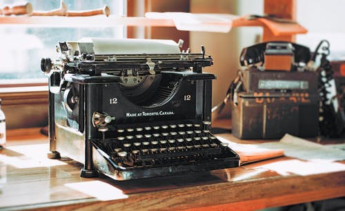 棕色的木桌上的经典黑色打字机 · 免费素材图片