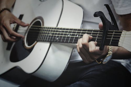 男子手持白色无畏原声吉他 · 免费素材图片