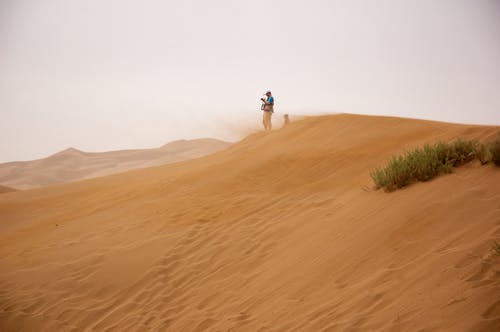 男子站在棕色的沙子，在灰色的天空下 · 免费素材图片