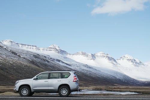 白雪皑皑的山附近道路上的灰色越野车 · 免费素材图片