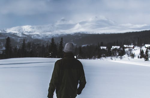 穿黑夹克的人在雪中行走 · 免费素材图片