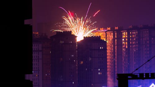 夜间在高层建筑物附近燃放烟花 · 免费素材图片