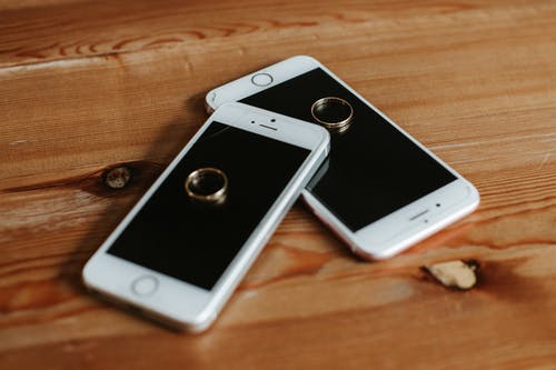 棕色木制表面上的两个玫瑰金iphone 6s · 免费素材图片