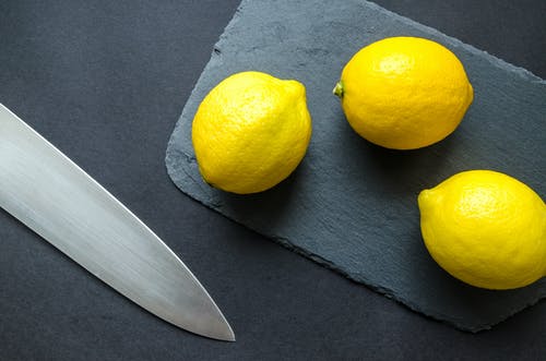 在刀子附近的砧板上的三个柠檬的照片 · 免费素材图片