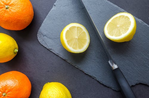 灰色表面上的两个橙色和三个柠檬 · 免费素材图片