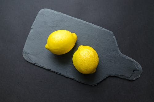 黑色木垫上的两个柠檬 · 免费素材图片