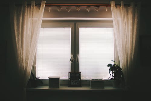 白色两窗格窗口附近的棕色窗帘 · 免费素材图片