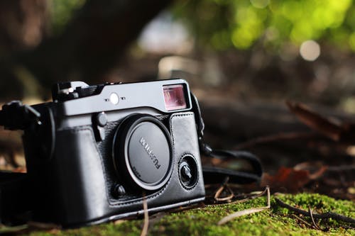 黑色富士胶片相机在地面上的选择性聚焦照片 · 免费素材图片