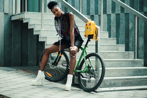 黑色无袖穿裙子坐在绿色的自行车上的女人 · 免费素材图片
