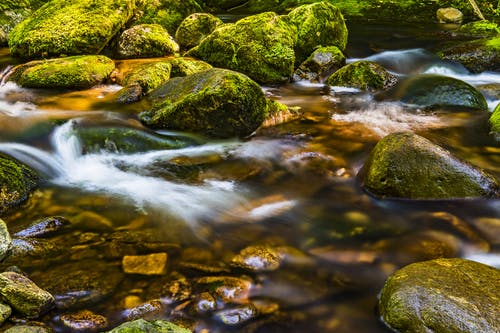河流流经苔藓覆盖的岩石的时光倒流摄影 · 免费素材图片