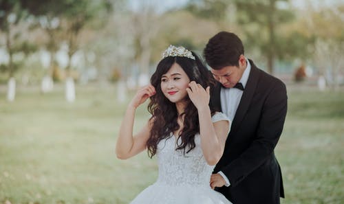 新郎在后面绑新娘的白色蕾丝婚纱 · 免费素材图片