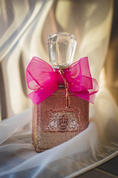 红丝带闪闪发光的粉红色香水瓶的特写照片 · 免费素材图片