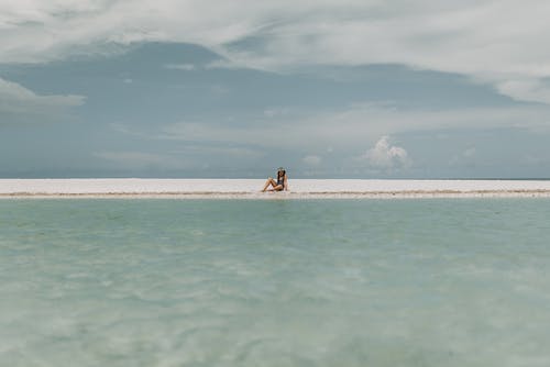 坐在白色的沙滩上的人 · 免费素材图片