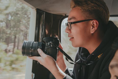 男子手持尼康单反相机的照片 · 免费素材图片