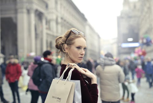 女人穿着栗色的长袖上衣，在选择性聚焦摄影中携带棕色和白色纸袋 · 免费素材图片