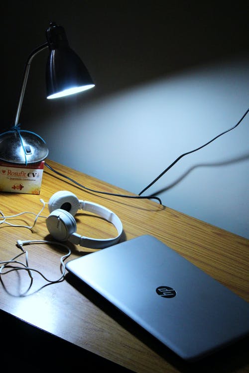 灰色的惠普笔记本电脑和棕色木制的桌子上的白色有线的耳机 · 免费素材图片