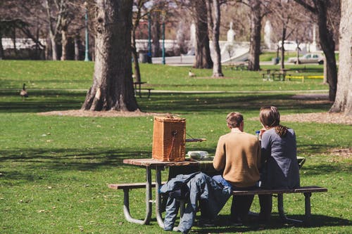 男人和女人坐在棕色的木制餐桌上 · 免费素材图片