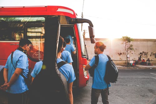 一群穿着蓝色衬衫的男人即将进入红色巴士 · 免费素材图片