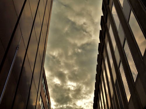 灰色多云的天空下的两座黑色高层建筑 · 免费素材图片