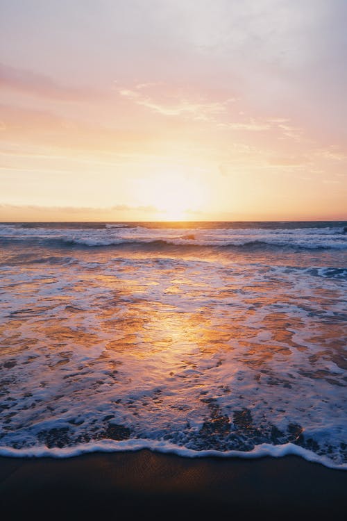 日落期间海浪在海边附近的照片 · 免费素材图片