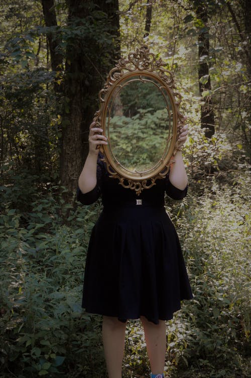 女人在森林中间反对她的头拿镜子 · 免费素材图片